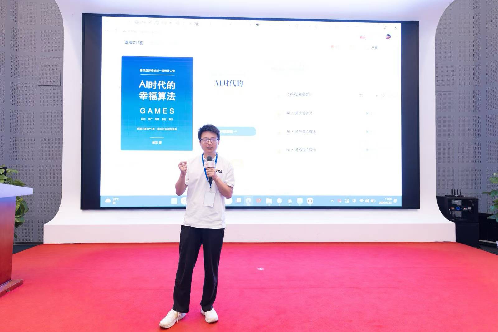 姚双在活动现场持麦克风分享，背后屏幕展示《AI时代的幸福算法》封面